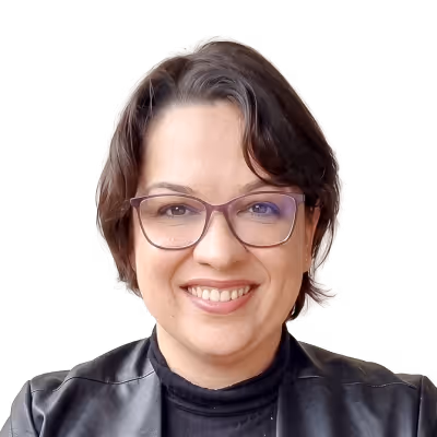 Mulher com cabelos longos e loiros apoiando o rosto na mão com fundo de plantas.